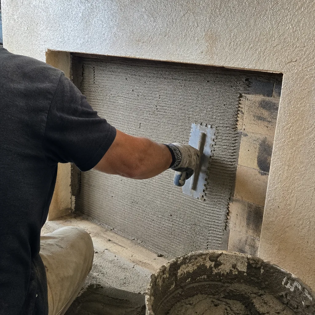 professional contractor applying mortar to fireplace wall for tile installation